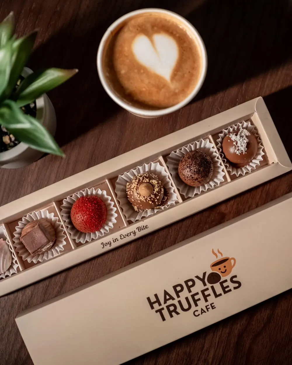 A long Happy Truffles box of five truffles next to a latte
